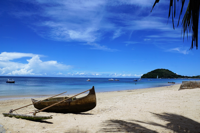 canoe on shore with deep blue water and mountains in the background